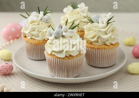 Tasty Easter cupcakes with vanilla cream and candies on table Stock Photo