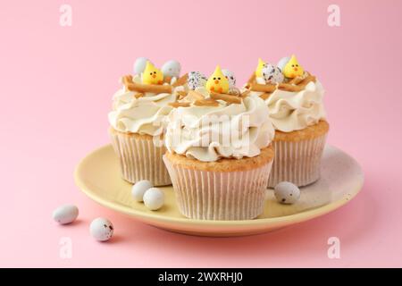 Tasty Easter cupcakes with vanilla cream and candies on pink background Stock Photo