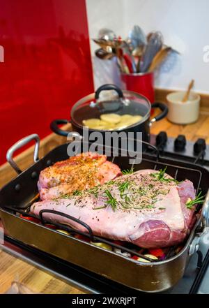Preparing a leg and small shoulder of lamb for roasting with garlic and  rosemary herbs Stock Photo