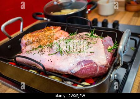 Preparing a leg and small shoulder of lamb for roasting with garlic and  rosemary herbs Stock Photo