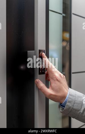 A vertical closeup shot of a person using an electronic door pad to enter an apartment Stock Photo