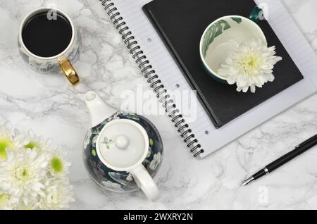 Coffee, white flowers, notebook, pen on a table, flat lay. Stock Photo
