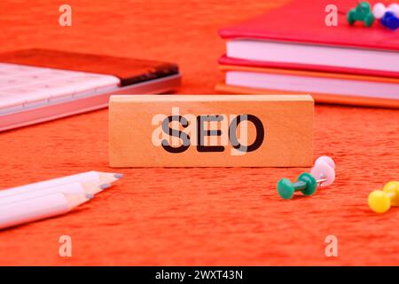 SEO Search Engine Optimization symbol on a wooden block next to office supplies Stock Photo