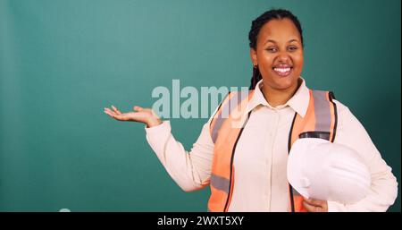 Young Black construction worker gestures smiling, working on site Stock Photo