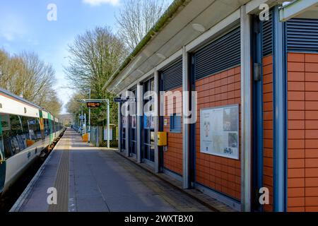 A Southern Railway train in green and yellow livery stands at almost empty railway station platform Stock Photo