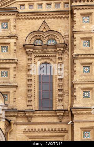 Fragment of the wall of an ancient Orthodox church with a picturesque window and decorative elements made of ceramics. Stock Photo