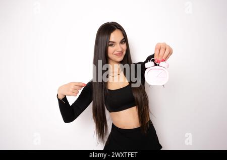 Photo portrait of positive woman holding clock with one hand pointing finger isolated on white background Stock Photo