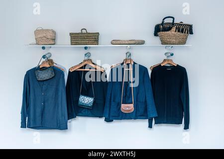 Jackets on hangers with bags on shelf in East London home, UK Stock Photo