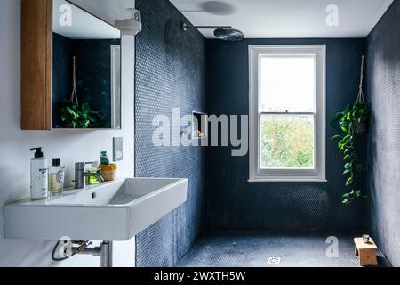 Stylish tiled wet room with sink and cabinet in East London home, UK Stock Photo
