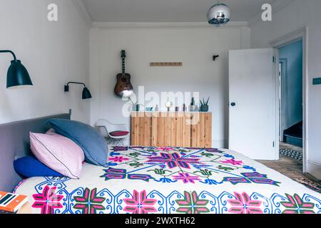 70's retro bedspread with guitar and open door in East London home, UK Stock Photo