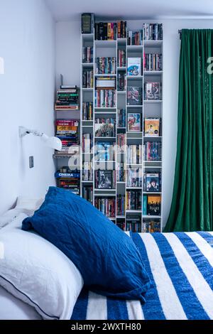 Striped blue and white bed cover with shelf organisers in East London, UK Stock Photo