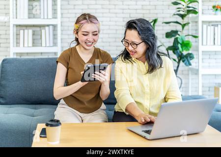 The beautiful mother and daughter working on the tablet and laptop Stock Photo