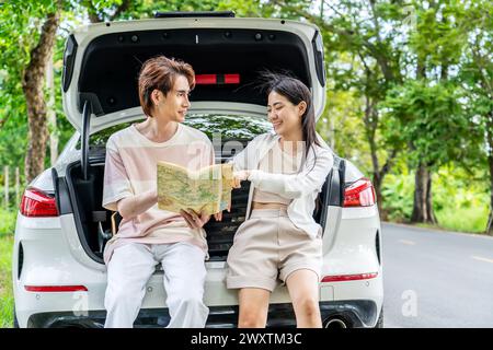 A young couple sitting in a car, looking at a map Stock Photo