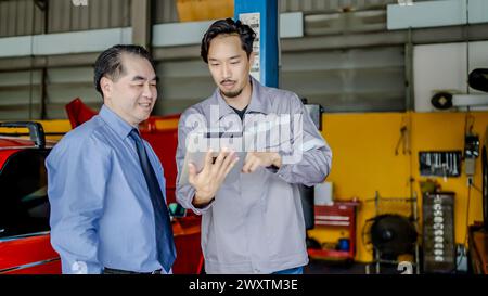 Two auto technicians using a digital tablet while repairing a car Stock Photo