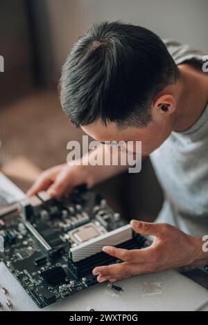 Circuit Expertise : With a steady hand, a computer engineer carefully secures a CPU into its socket, a testament to the blend of technology and manual Stock Photo