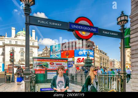 Pedestrians walking past the famous Piccadilly Circus station on a sunny day. Stock Photo
