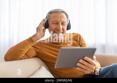 Elderly man with headphones using a tablet Stock Photo