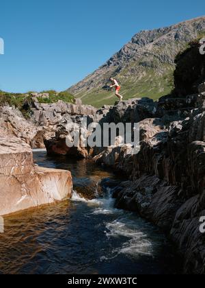 Jumping into the River Etive running through Glen Etive is a glen in the Highlands of Scotland, UK - mountain river landscape Stock Photo