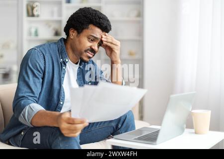 Concerned Black Man Reviewing Documents at Home Stock Photo