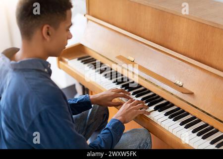Focused black teen guy practicing piano at home Stock Photo
