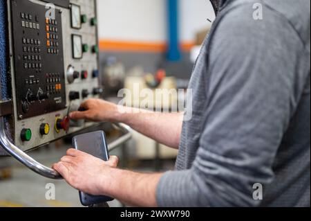 Worker pressing buttons on CNC machine control board in factory. High quality photography. Stock Photo
