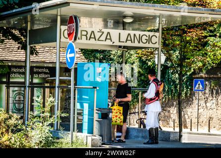Random man along side costumed man in Croatian regalia at a tram stop and ticket machine in downtown Zagreb in Croatia Stock Photo