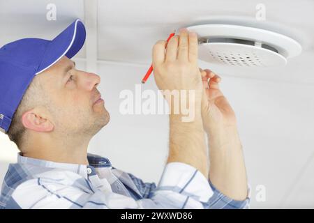 technician reaching up to open filter holder in ceiling Stock Photo