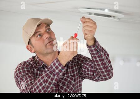 a workman is securing screws on ceiling Stock Photo