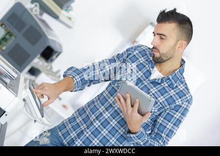 technician using a tablet to fix a printer Stock Photo