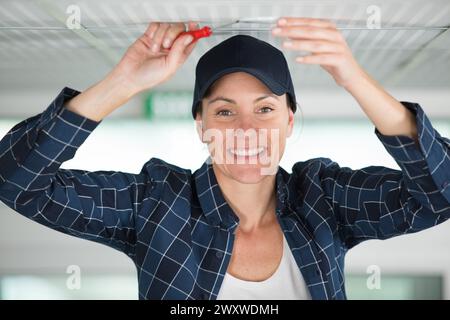 happy female builder using screwdriver on wooden beam Stock Photo