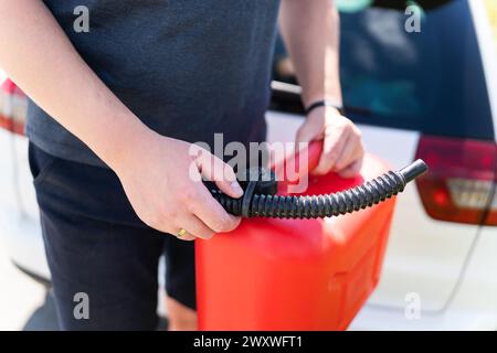 A person pouring gasoline from a red can into a car during an emergency refill Stock Photo