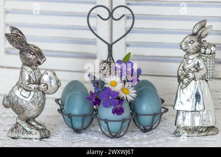easter arrangement with easter bunny and  blue coloured eggs decorated with periwinkle, daisy flowers and grape hyacinths Stock Photo