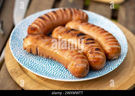 plate of freshly grilled sausages on picnic table in garden party Stock Photo