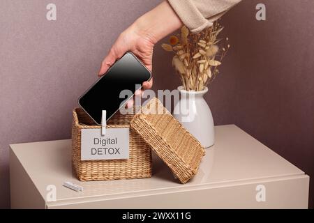 Woman putting phone into box with different gadgets at home Stock Photo