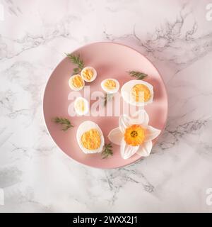 Boiled chicken and quail eggs and narcissus on pink plate on kitchen marble background. Healthy raw food concept Stock Photo