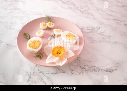Boiled chicken and quail eggs and narcissus on pink plate on kitchen marble background. Healthy raw food concept Stock Photo