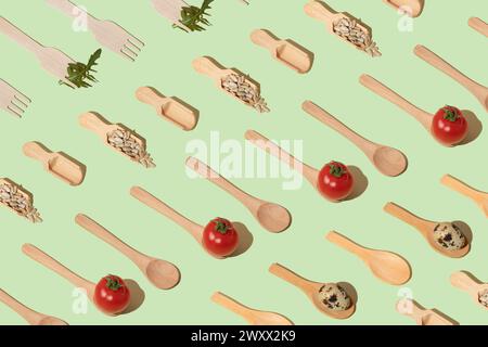 Wooden kitchen cutlery, cherry tomatoes, quail eggs, sunflower seeds on mint background. Flat lay pattern Stock Photo