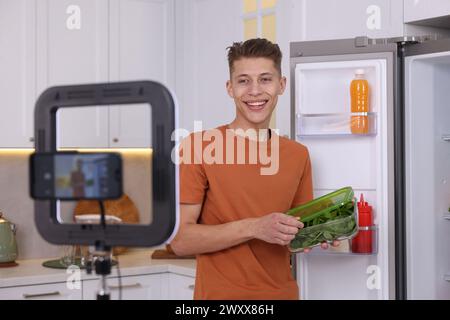 Smiling food blogger explaining something while recording video in kitchen Stock Photo