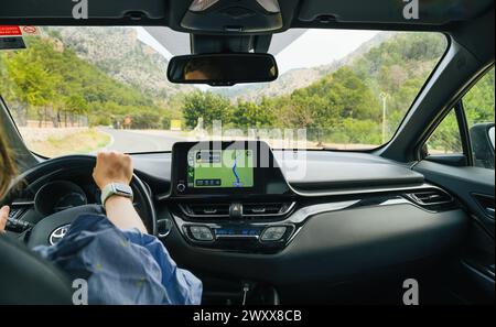 Mallorca, Spain - Jun 28, 2023: POV - a woman driving a car with one hand on the steering with Apple Computers CarPlay dashboard as GPS device for navigation Stock Photo