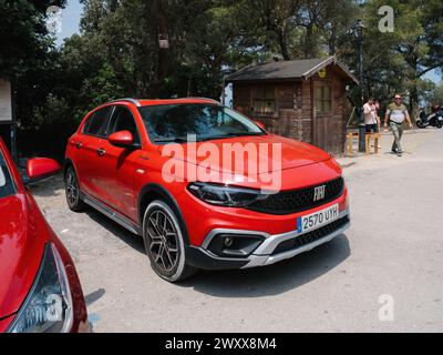 Mallorca, Spain - Jun 28, 2023: A vibrant red Fiat car is parked neatly by the side of the road, under a clear blue sky on a sunny day near Sa Foradada, Mallorca, Spain Stock Photo