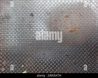 Olld worn grungy metal diamond plate pattern. Metallic industrial non-slip steel tread repetitive diagonal oval shape pattern, embossed steel surface Stock Photo