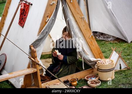 A young girl dressed in traditional Middle Age clothes sits in a tent during 'Rekawka' festival - a Slav, pre-Christian tradition celebration on Krakus Mound in Krakow. 'Rekawka' is known as the day of the death celebrated by pagan Slavs in the region. It is celebrated now on the first Tuesday after Easter. Pagan and pre-Christian traditions is very popular now and is seen as an important component in Polish heritage. Stock Photo