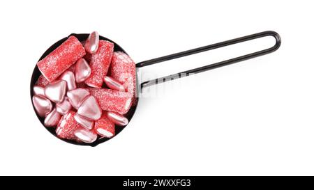 Yummy candies in measuring cup isolated on white, top view Stock Photo