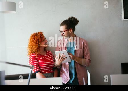 Friendly happy multiethnic coworker male and female having fun with tablet, working together Stock Photo