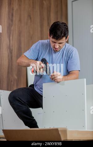 Man assembling furniture by using cordless screwdriver. Stock Photo