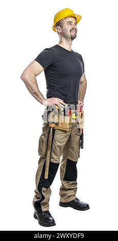 Confident construction worker stands with hands on hips, wearing a hard hat and tool belt, isolated on white Stock Photo