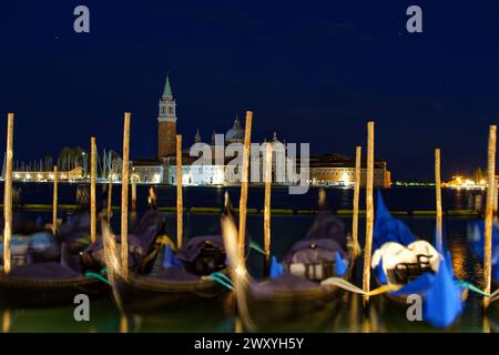 Italy, Venice: night view of gondolas moored at the San Marco dock, with the San Giorgio Maggiore Basilica in the background Stock Photo