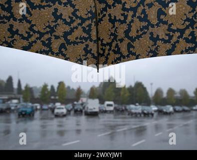 walking in the rain under an umbrella to a parking lot Stock Photo
