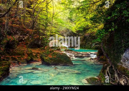 Lush greenery surrounds the tranquil turquoise waters cascading through Urbasa Forest, creating a serene, magical landscape Stock Photo
