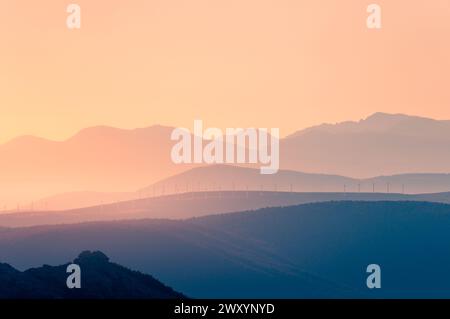 A tranquil sunset over the layered silhouettes of Siete Picos in the Sierra de Guadarrama, with soft pastel colors gracing the sky Stock Photo